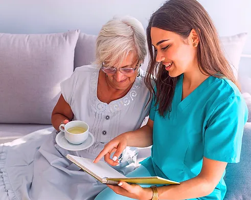 A woman in scrubs reviewing a notebook with an older woman